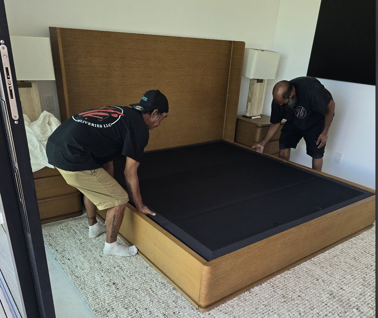 Two Hi.Deliveries crew members assembling a bed frame in a bedroom