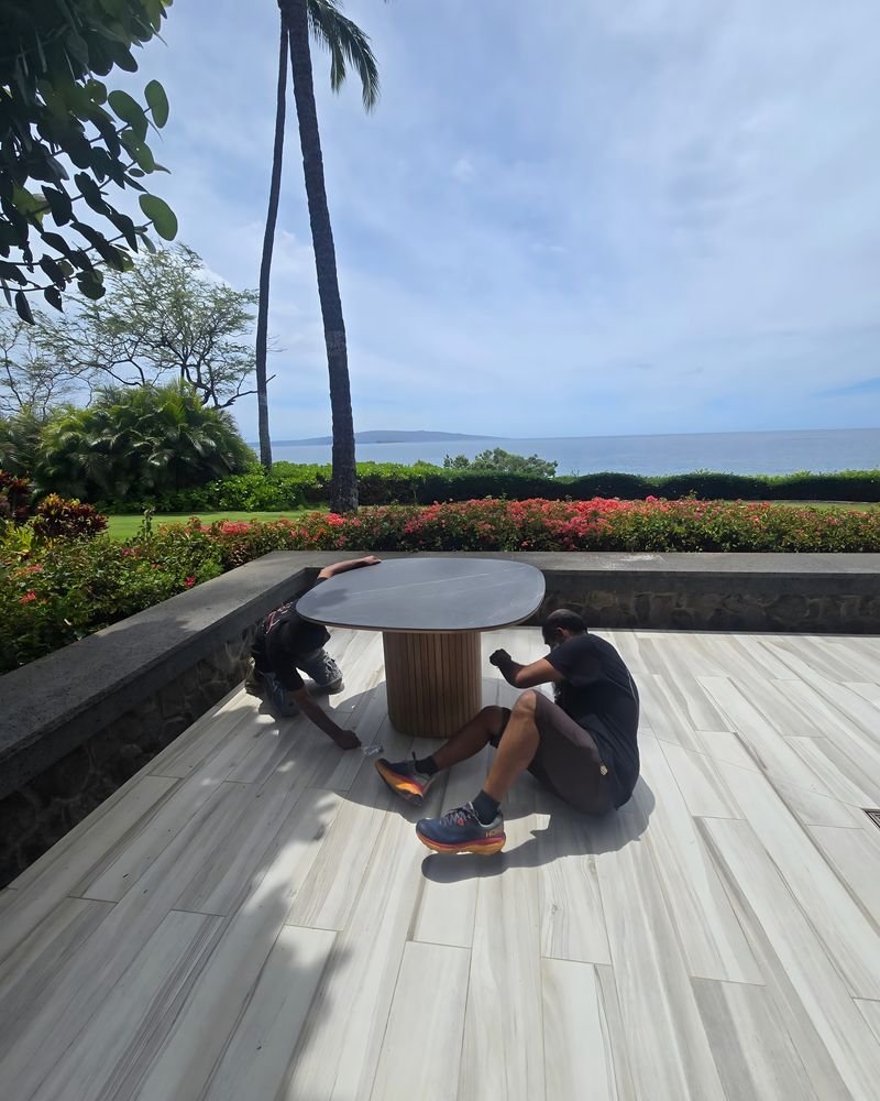 Two people working at a round table on an ocean-view patio