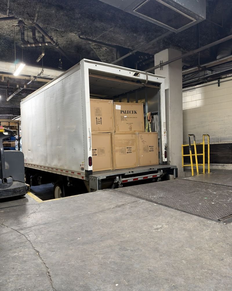 A box truck backed into a loading dock with cartons stacked inside